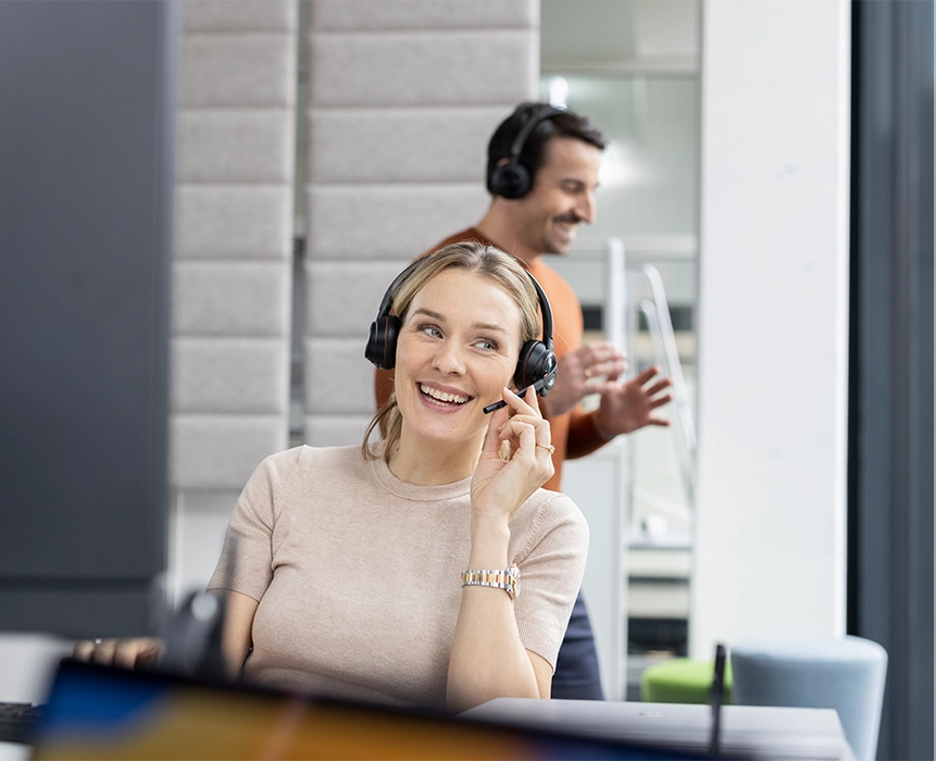 Zwei Bechtle-Mitarbeitende, im Vordergrund eine Frau mit Headset während eines Anrufs.